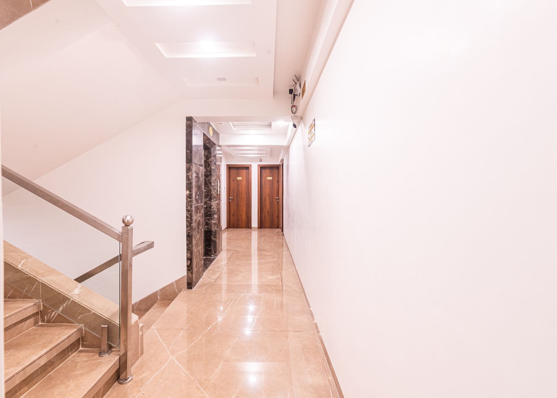 A quiet corridor of polished cream stone and walnut doors
