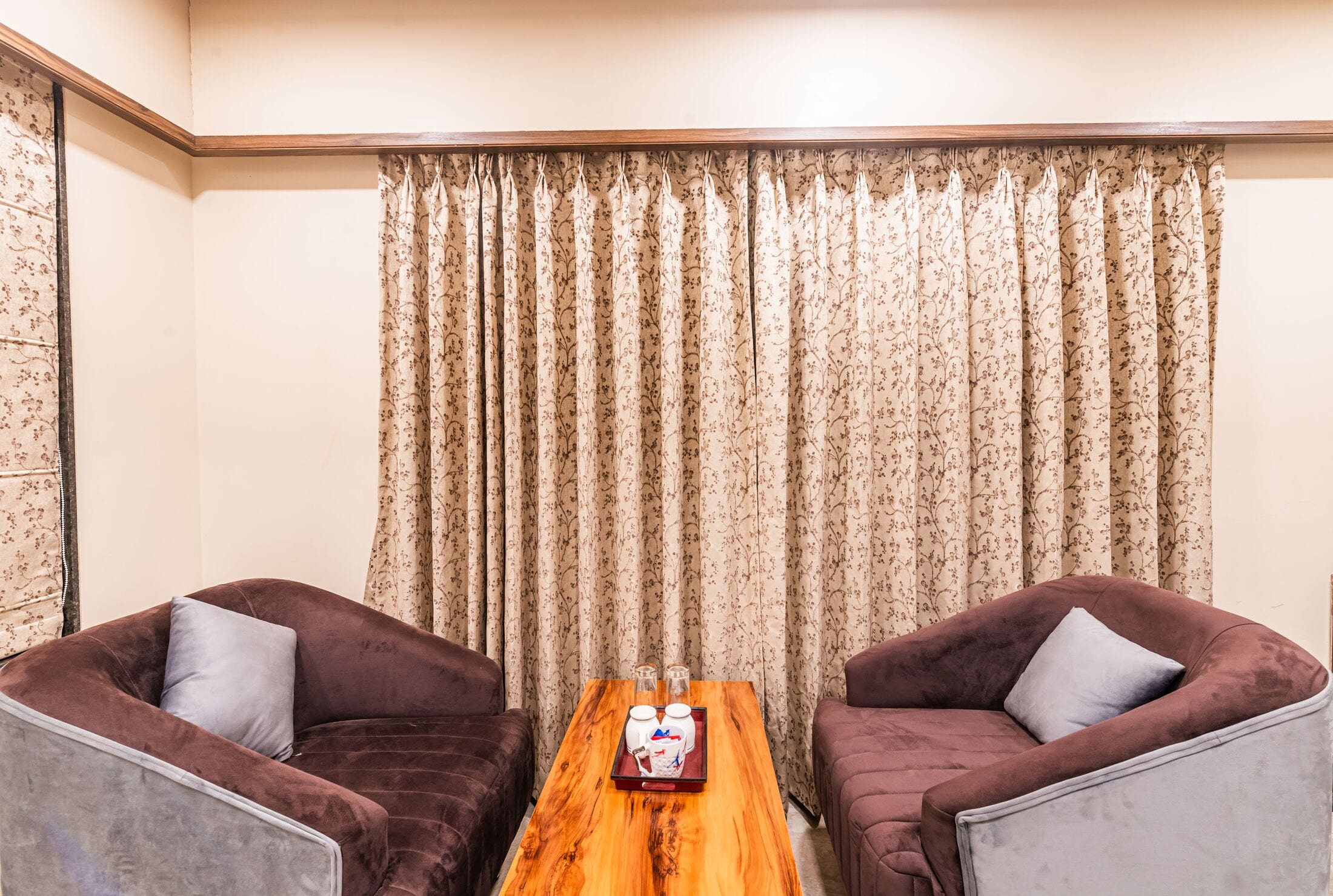 Two plum velvet tub armchairs around a timber coffee table