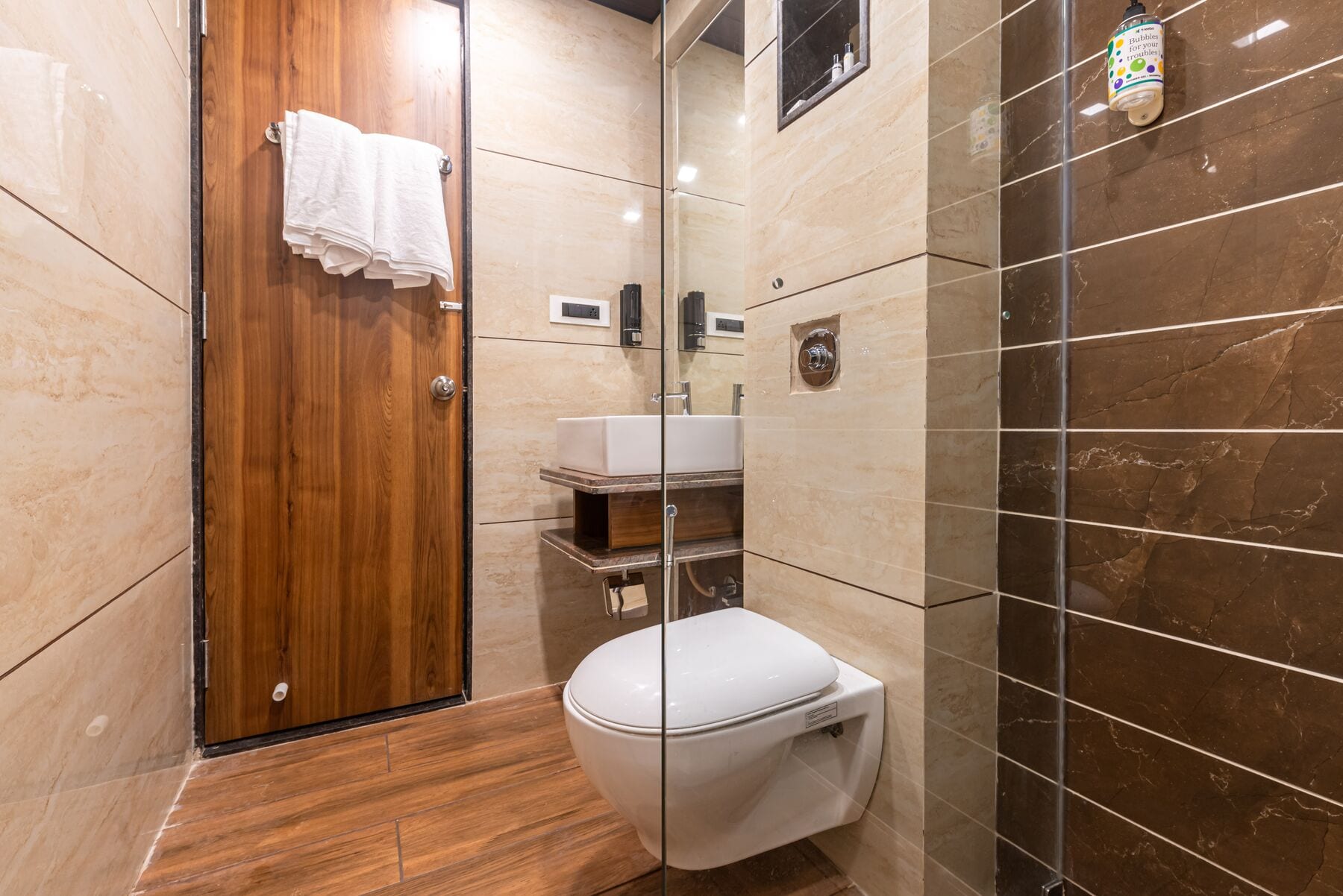 The Super Deluxe bathroom: stone tiles, a walnut door and a glass shower