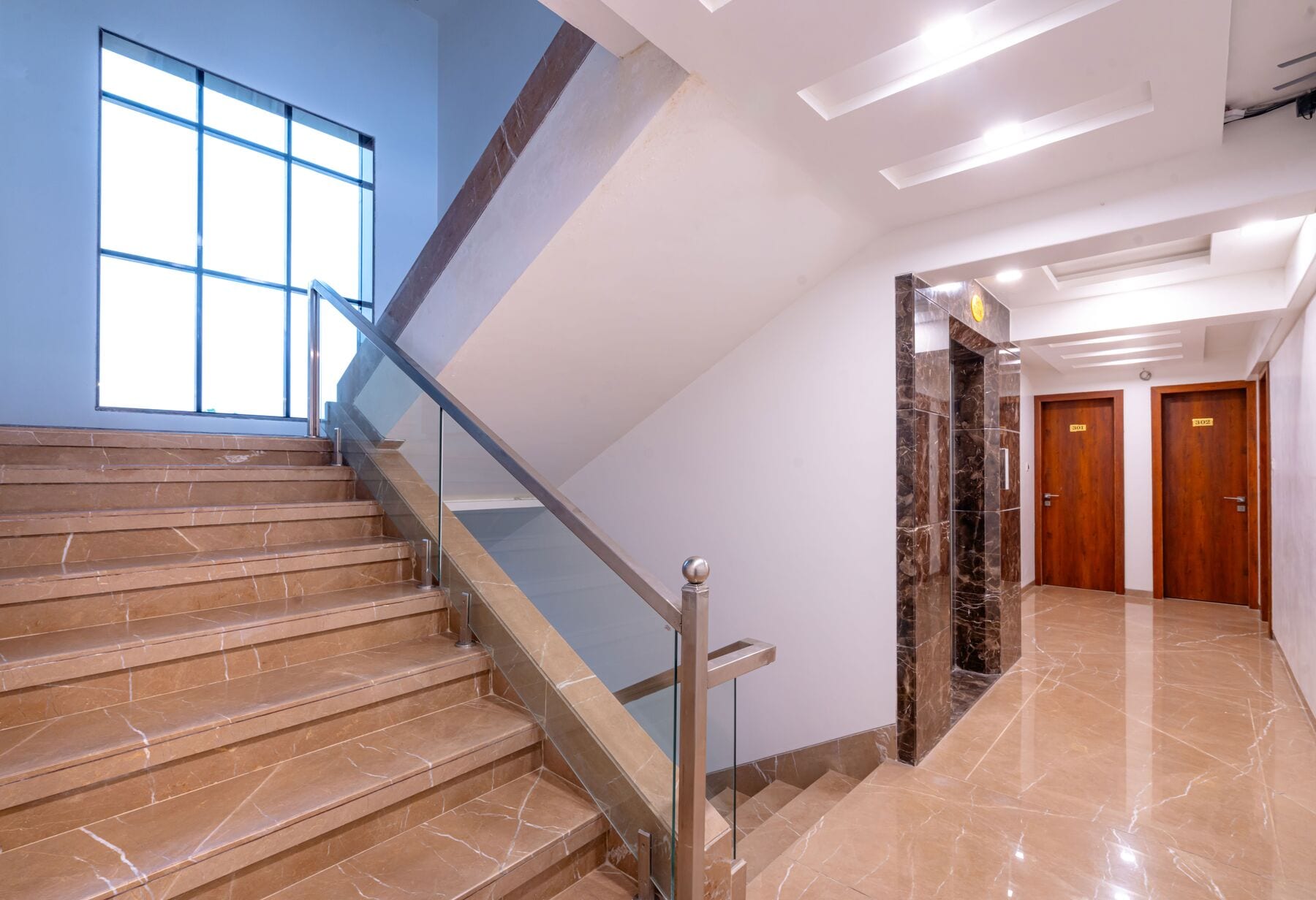 The stair: cream stone steps, glass balustrade and a tall window