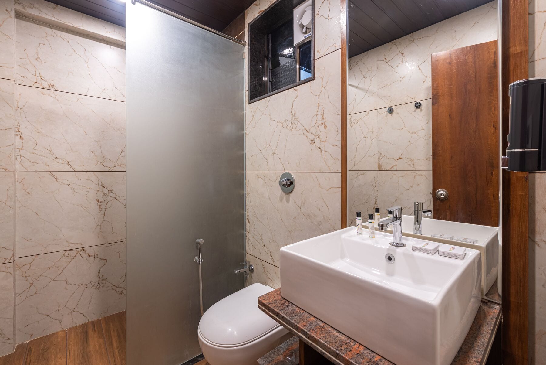 The Suite bathroom: marble-clad walls, a vessel basin and frosted glass