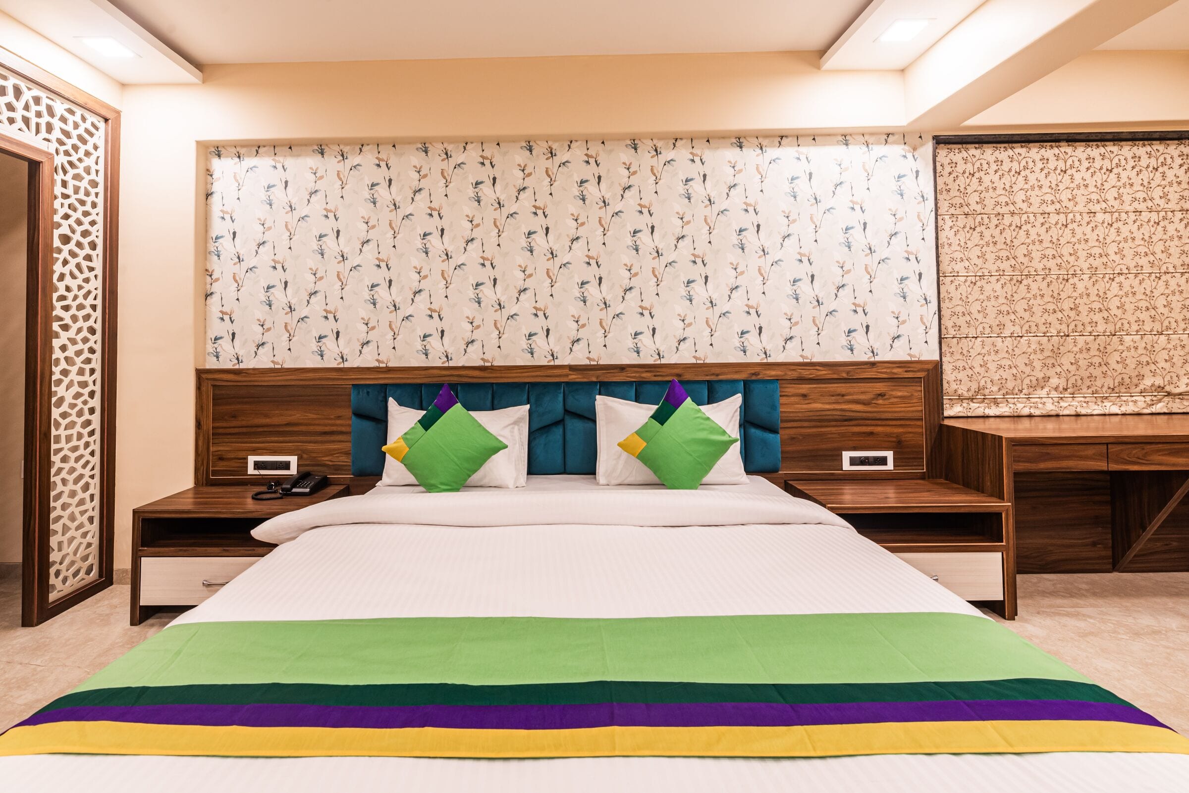 The Suite bed, straight on: teal channel-tufted headboard and botanical wallpaper