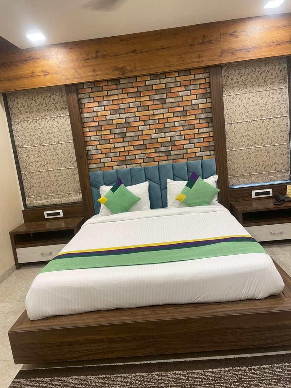 The Deluxe room: a teal padded headboard against a brick feature wall