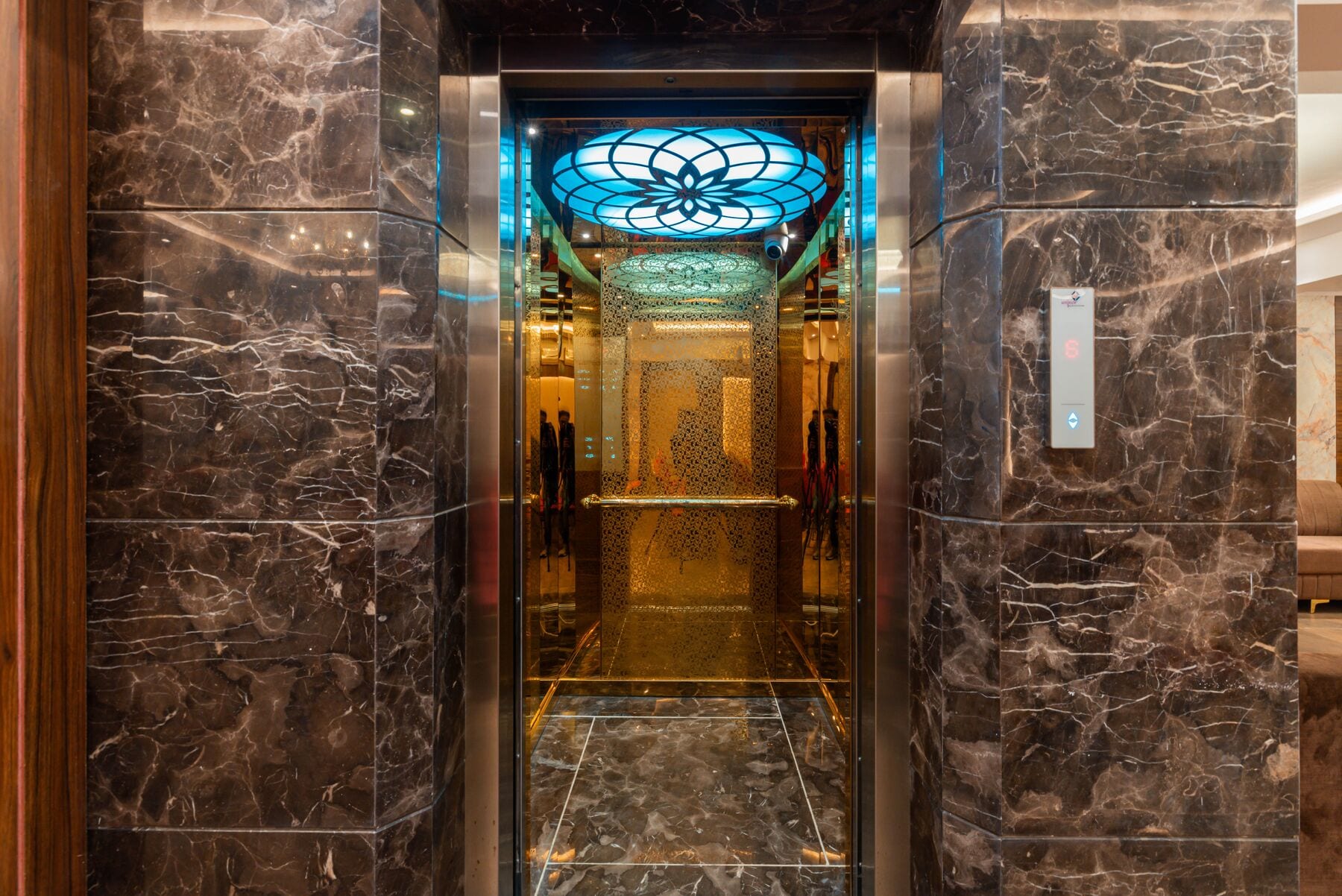 The lift: dark marble walls and a glowing lotus-patterned glass ceiling