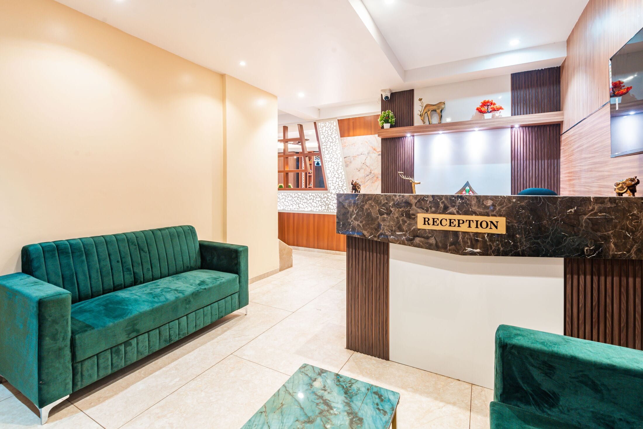 Reception: emerald velvet sofas, a green onyx table on a brass frame and the marble-topped desk